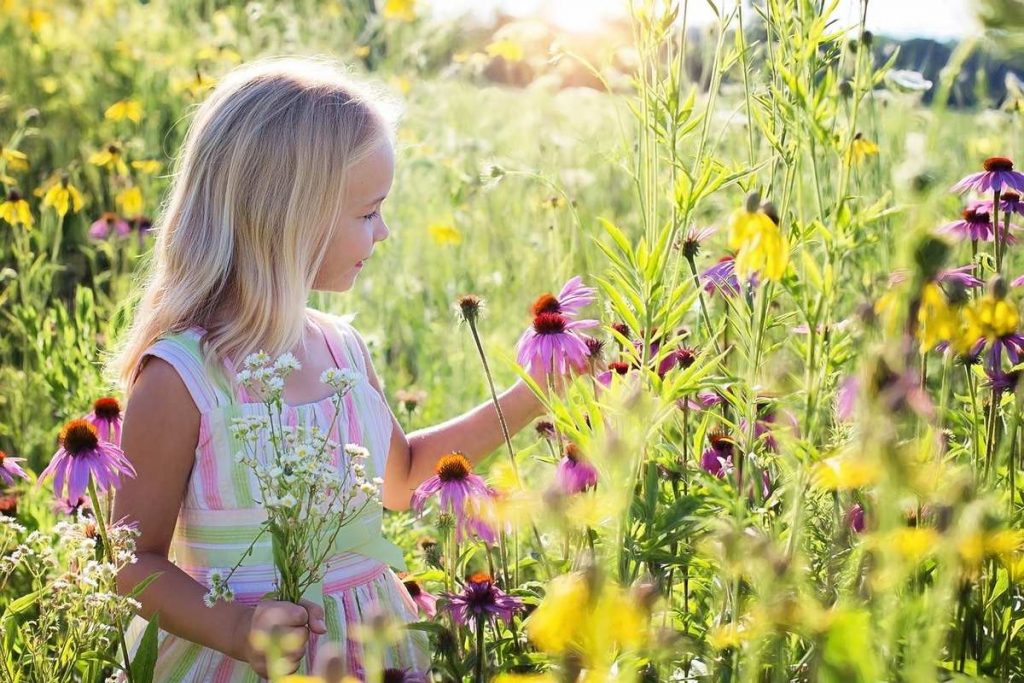 una niña en un jardín lleno flores