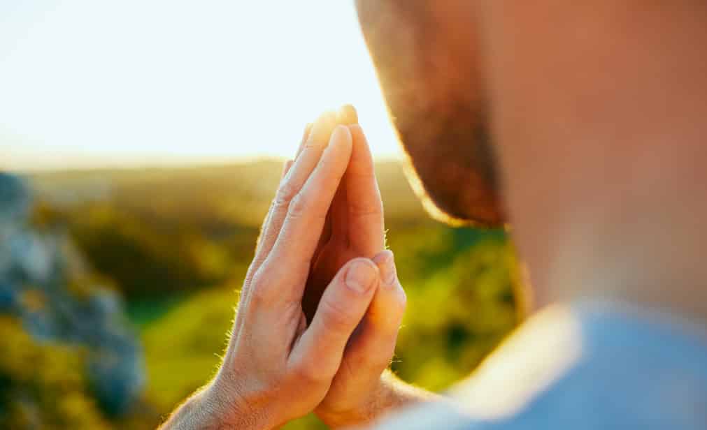 hombre rezando en el campo que evoca el sentimiento de gratitud