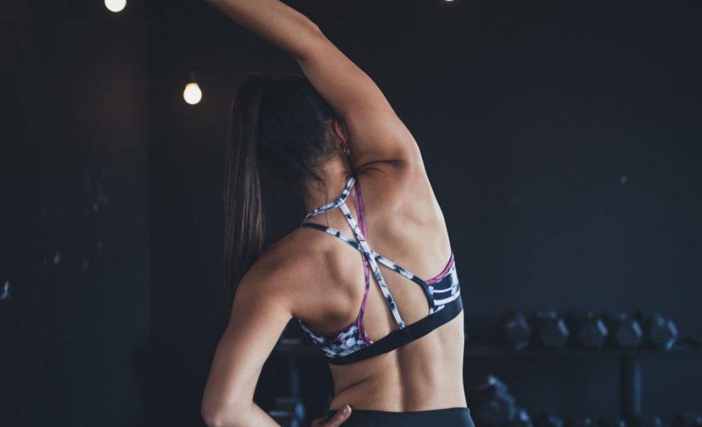 Mujer estirando antes de un entrenamiento con pesas en el gimnasio